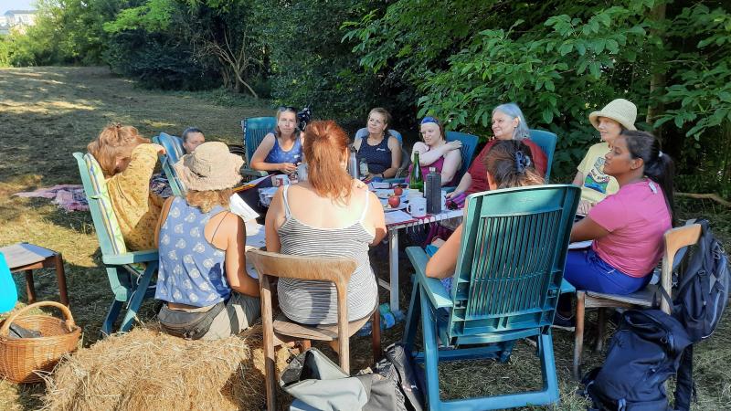 Eine Gruppe Frauen sitzt im Kreis im Garten.